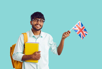 Studying in England. Portrait of happy Indian male university student with UK flag on light blue...