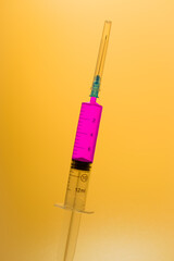 Medical syringe with legendary purple vaccine against corona virus and monkeypox on a yellow background. Medical treatment. Vaccination in laboratory. Medical experiment.