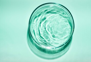 Blue green cosmetic liquid on Petri dish. Tonic or toner serum gel swath. Mock up