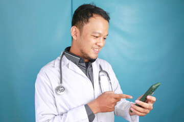 Young Asian man doctor is smiling and pointing his smartphone
