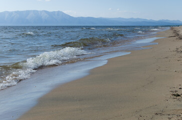 Beautiful seascape. The waves of Lake Baikal wash the sandy shore.