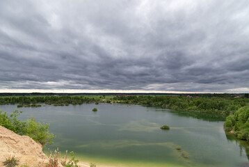 A lake with a sandy mountain. Like on Mars. An unusual lake shore. Stormy sky. Martian species. Lake with green water