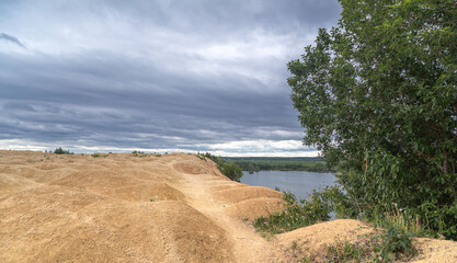 A lake with a sandy mountain. Like on Mars. An unusual lake shore. Stormy sky. Martian species