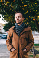 Fototapeta premium close-up guy in a jacket on a background of orange tree and street. portrait.