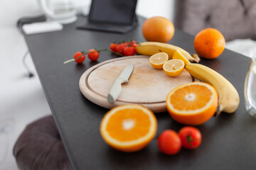 Healthy food concept. Sliced oranges and lemons, bananas and cherry tomatoes on kitchen countertop