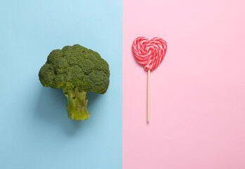 Healthy versus junk food. Broccoli and lollipop on a blue-pink background. Weight loss, diet concept