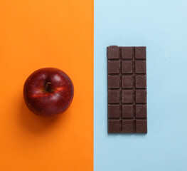 Apple and chocolate bar on colored background