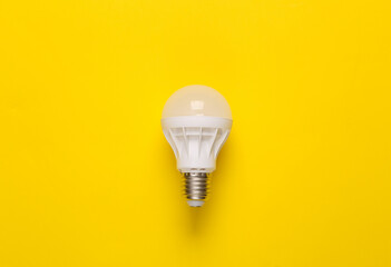 Economy led light bulb on yellow background. Top view