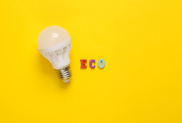 Eco concept. Led light bulb with word eco on yellow background. Top view