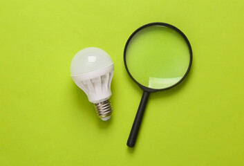 Led light bulb with magnifying glass on green background. Search for creative idea