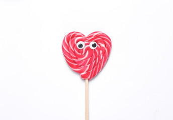 Minimal food conceptual pop still life. Heart shaped lollipop with goggles on white background