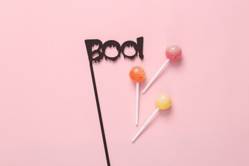 The word boo! with lollipops on a pink background. Halloween, trick or treat still life