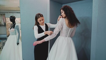 A wedding salon consultant measures the sleeve length of the bride's wedding dress. Slow motion