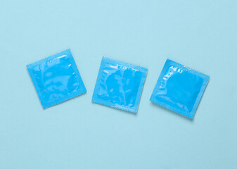 Three packs of condoms on a blue background