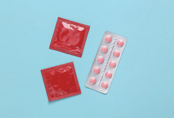 Contraceptives. Condoms and birth control pills on blue background.