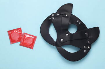 BDSM leather cat mask with condom packages on a blue background. Sex games. Top view