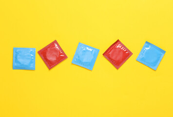 Red and blue packs of condoms on a yellow background. Top view