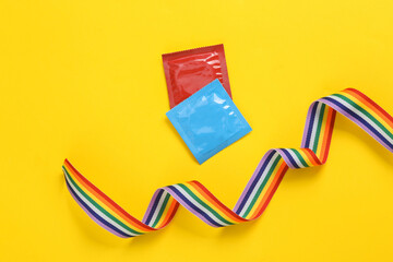 Packs of condoms with lgbt rainbow tape on a yellow background. Same sex relationship concept