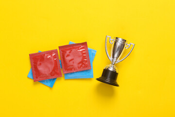 Macho, alpha male. Condoms with winner cup on yellow background