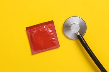 diagnosis and prevention of sexual diseases. Pack of condom with stethoscope on yellow background