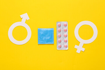 Condoms packaging and blister of birth control pills, male and female gender symbol on yellow...