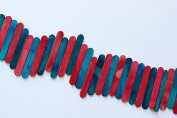 blue and red wood sticks arranged somewhat diagonally on a light paper surface