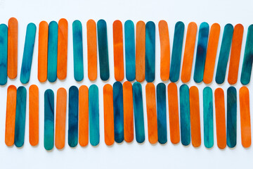 two rows of orange and blue wood sticks arranged on a paper surface