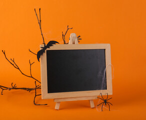 Halloween decor with empty chalk board on orange background. Happy halloween, trick or treat