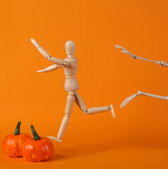 The skeleton is chasing a wooden puppet on an orange background. Halloween concept