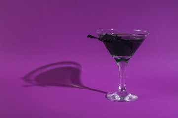 Halloween party. Cocktail with green liquid and bats on purple background