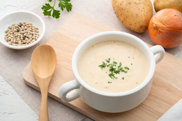 Bowl of creamy potato soup on wooden plate