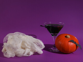 Halloween party. Cocktail with green liquid and bats, pumpkin and mummy bandages on purple background with shadow
