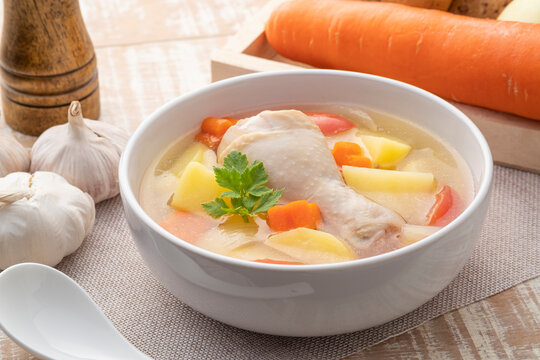 Clear chicken soup with potatoes carrot and onion in white bowl.Asian style food