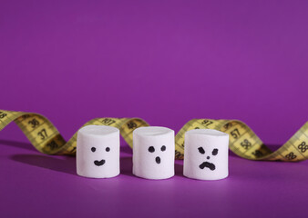 Marshmallows with faces and a measuring tape on a purple background