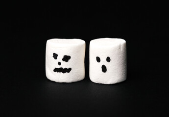 Halloween marshmallows with faces on a black background