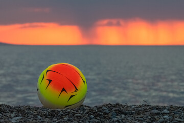 Close up of a volleyball against a dramatic and vivid sunset.
