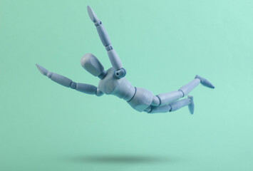 Falling down wooden puppet on blue background