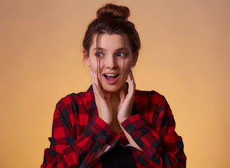 Image of excited screaming young woman standing isolated over yellow background in checkered shirt . Looking camera, people sincere emotions lifestyle concept. Mock up copy space.