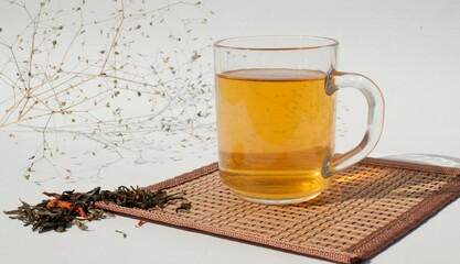 Green tea in a glass transparent cup and a branch of dried flowers on a white background