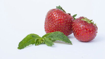Ripe red strawberries and mint leaves on a white, pastel background