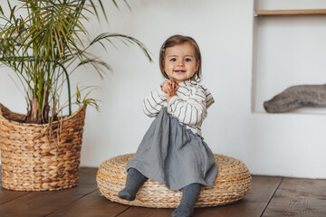 Pretty one year toddler girl in grey and white stripped dress posing in eco studio. Copy space.