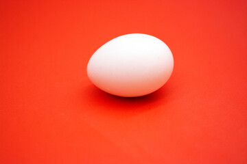 One white raw eggs lie on the red surface of the table in the kitchen. Horizontal photo, large egg. Preparing for Easter. Easter Ingredients