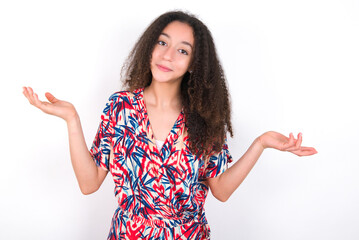 Cheerful young beautiful girl with afro hairstyle wearing flowered dress making a welcome gesture raising arms over head.