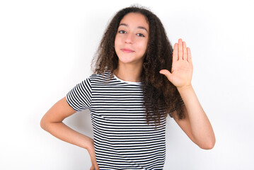 young beautiful girl with afro hairstyle wearing striped t-shirt over white wall waiving saying hello or goodbye happy and smiling, friendly welcome gesture.