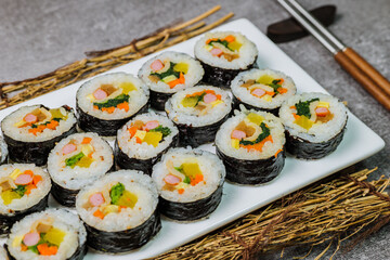 Korean food Gimbap : Rice seasoned with salt and sesame oil and rolled up in a sheet of roasted gim (dried laver) with spinach, carrots, and pickled white radish. The long roll is sliced and served in