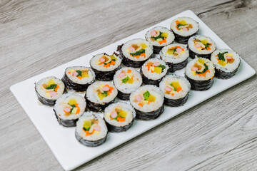 Korean food Gimbap : Rice seasoned with salt and sesame oil and rolled up in a sheet of roasted gim (dried laver) with spinach, carrots, and pickled white radish. The long roll is sliced and served in