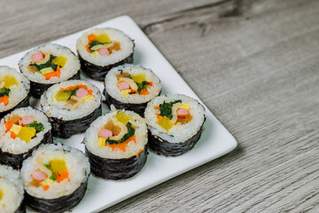 Korean food Gimbap : Rice seasoned with salt and sesame oil and rolled up in a sheet of roasted gim (dried laver) with spinach, carrots, and pickled white radish. The long roll is sliced and served in