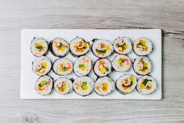 Korean food Gimbap : Rice seasoned with salt and sesame oil and rolled up in a sheet of roasted gim (dried laver) with spinach, carrots, and pickled white radish. The long roll is sliced and served in