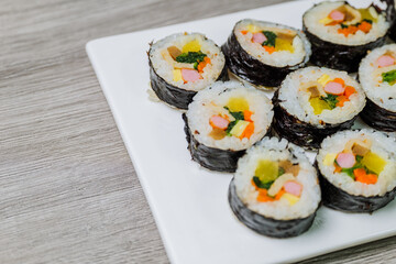 Korean food Gimbap : Rice seasoned with salt and sesame oil and rolled up in a sheet of roasted gim (dried laver) with spinach, carrots, and pickled white radish. The long roll is sliced and served in