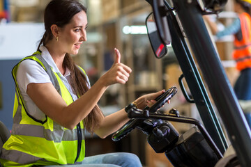 women worker at forklift driver happy working in industry factory logistic ship. Woman forklift driver in warehouse area. - obrazy, fototapety, plakaty